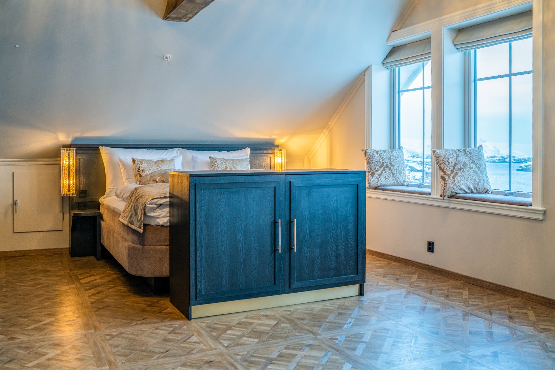 URE suite — bed beneath the eaves with a cushioned window seat over the snowy shore